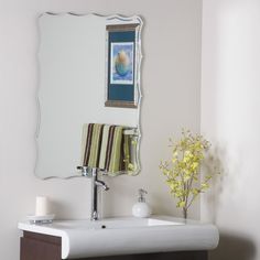 a bathroom with a sink, mirror and flowers on the counter top in front of it