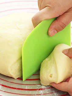 a person is cutting some bread on a plate with a green spatula and knife