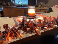 a candle sitting on top of a kitchen counter next to some candy wrapper wrapped around it