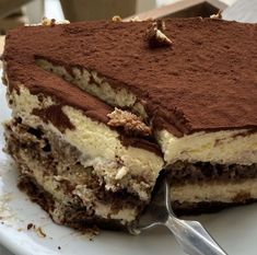 a piece of cake on a white plate with a fork in it and chocolate frosting