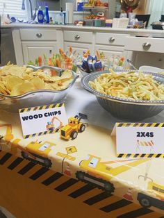 a table topped with bowls filled with food next to construction themed plates and place cards