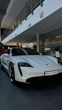 a white sports car is parked in front of a large building with glass windows and balconies