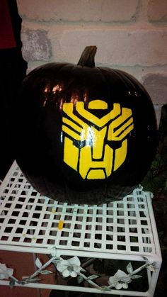 a black and yellow painted pumpkin sitting on top of a white shelf next to a brick wall