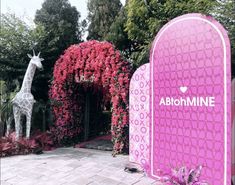 a giraffe statue is in front of a pink arch with the word abotmine on it