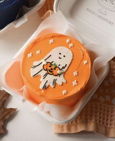 an orange cake decorated with a ghost and pumpkin