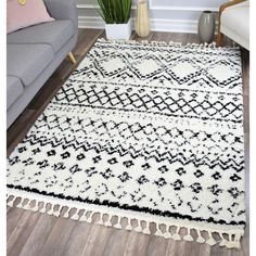 a black and white rug with tassels on the floor next to a couch