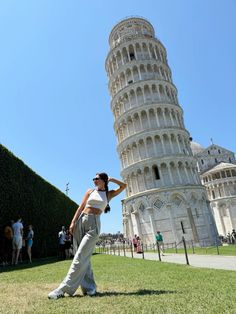 a woman is standing in front of the leaning tower