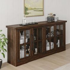 a large wooden cabinet with glass doors in a living room next to a potted plant