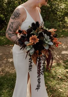 a woman in a white dress holding a bouquet with flowers on her chest and arm