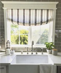 a kitchen sink sitting under a window next to a potted plant