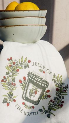 two lemons are sitting in a bowl on top of a towel that says jelly of the month