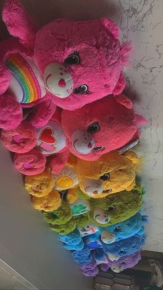 there are many stuffed animals hanging on the wall with rainbows and hearts around them