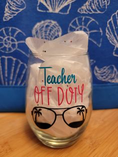 a glass with the words teacher off duty written on it and sunglasses in front of a blue wall