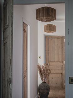 an entry way with a vase on the floor and two wooden doors in the background