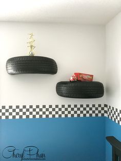 two black tires mounted to the wall in a room with checkered flooring and blue walls