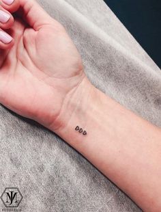 a woman's arm with the word love tattooed on her left wrist and two small hearts