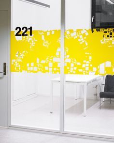 an office with yellow squares on the wall and white desks in front of it