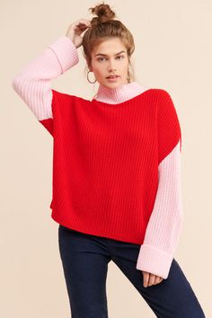 a woman in a red and white sweater is posing for the camera with her hand on her head