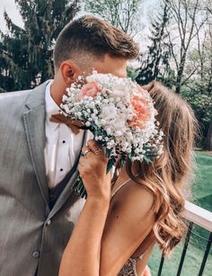 a man in a suit and tie kissing a woman with flowers on her face while she is wearing a dress