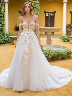 a woman in a wedding dress standing on a patio with columns and greenery behind her