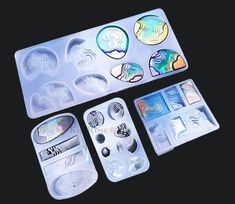 an assortment of different shapes and sizes of buttons in plastic trays on a black surface