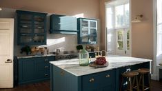 a kitchen with blue cabinets and marble counter tops