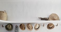 several hats are hanging on a white shelf