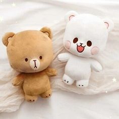 two teddy bears sitting on top of a white sheet