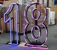 a large neon sign with the number eighteen on it's stand in a warehouse