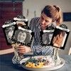 a woman sitting at a table with three pictures on it and one is holding a plate full of food