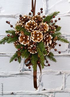 a bouquet of pine cones and berries hanging on a brick wall with the words diy pine cone kissing ball