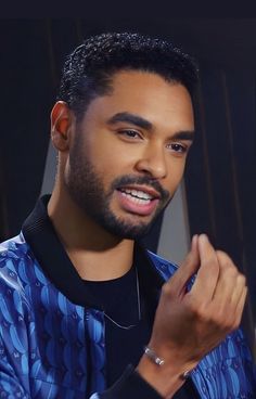 a close up of a person wearing a blue shirt and black jacket with his hand in his pocket