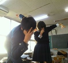 two people standing in front of a blackboard while one person holds his head up