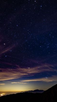 the night sky is filled with stars and clouds, as seen from a hill top