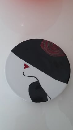 a white plate with a black and red design on the top, sitting on a table