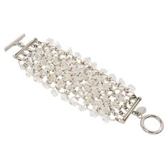 This gorgeous Paco Rabanne Paris futuristic link bracelet features a massive silver-tone chainmail grid ornate with dangle transparent quartz chips. The bracelet closes with a large toggle closing clasp, and the Paco Rabanne brand logo tag is attached to the fastening. The bracelet is in excellent condition, with minimal wear on the metal. This bracelet is embellished with natural material (quartz), so expect some minor flecks or irregularities. Measurements: 8.69 in long (22 cm) x 2.50 in wide