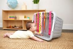 a baby laying on the floor next to a basket