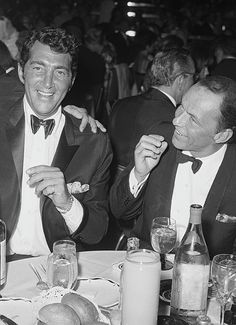 two men in tuxedos sitting at a table