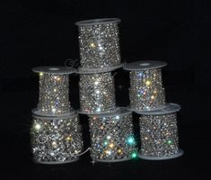 several spools of glitter sitting on top of each other in front of a black background