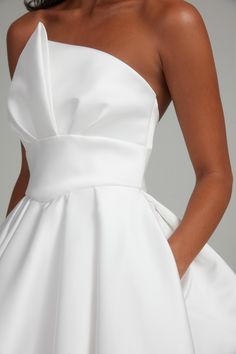 the back of a woman's white wedding dress, with her hands on her hips