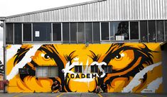 a yellow and black tiger painted on the side of a building next to a parking lot