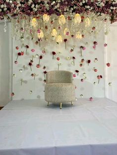 a chair sitting on top of a table under a flower covered ceiling with hanging lights