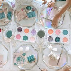 people sitting at a table with various paints and brushes