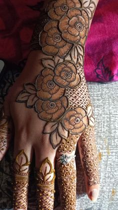 a woman's hand with hennap and flowers painted on it, showing the intricate