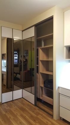 an empty room with mirrored closet doors and shelves in the corner, while someone is taking a photo