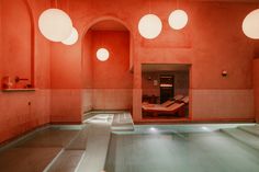 an indoor swimming pool with red walls and round lights hanging from it's ceiling