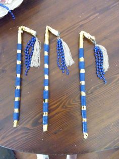 three blue and gold beaded sticks on a wooden table