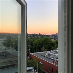 an open window looking out onto a city at sunset or sunrise with the sun setting