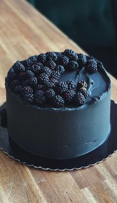 a chocolate cake topped with blackberries on top of a wooden table