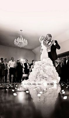 a bride and groom dance on the dance floor in front of their wedding party guests